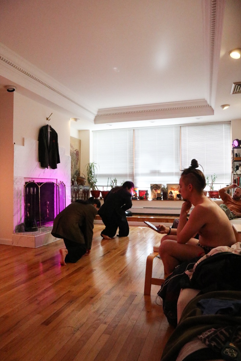 Maqs directing dancers in the studio — magenta light, Chelsea skyline behind