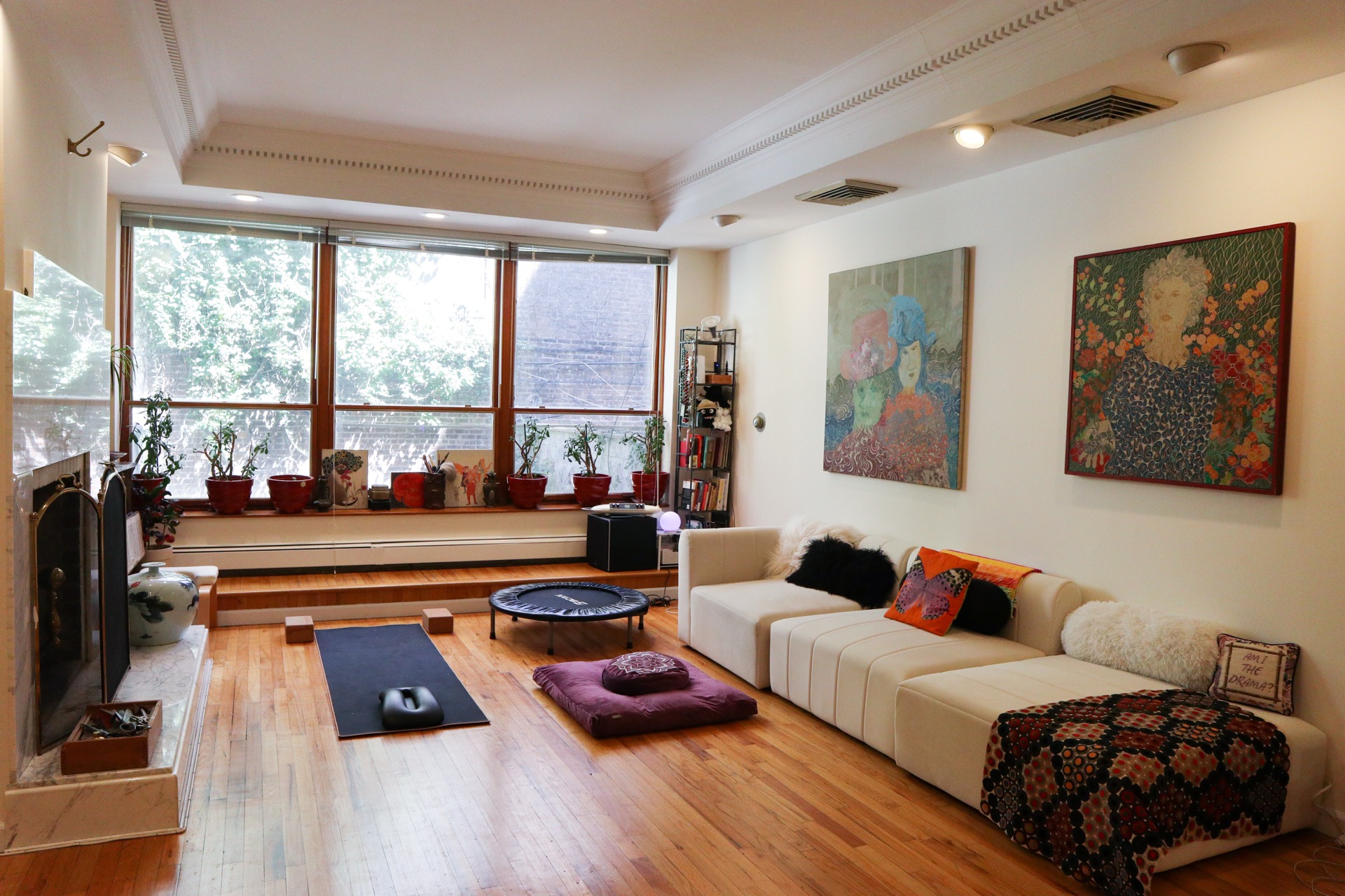 The main studio open and clear — yoga mat, movement, and Blossom's paintings holding the walls